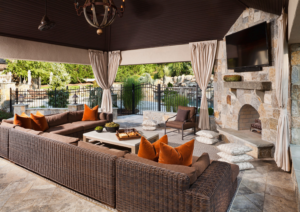 Ejemplo de patio mediterráneo extra grande en anexo de casas y patio trasero con chimenea y adoquines de piedra natural