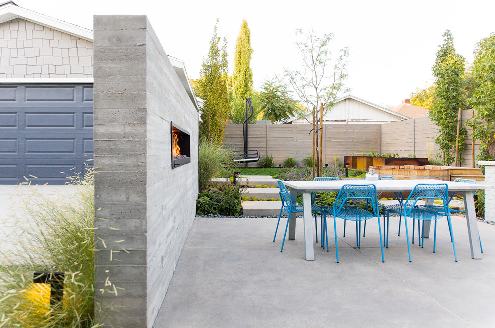 Стильный дизайн: двор на боковом дворе в современном стиле с уличным камином и покрытием из бетонных плит без защиты от солнца - последний тренд