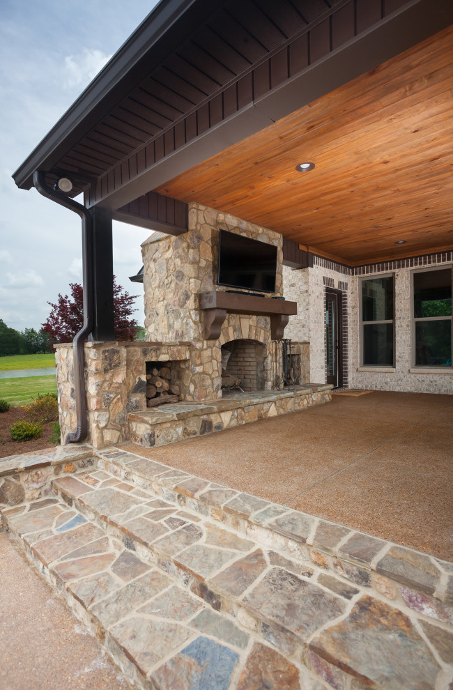 Immagine di un grande patio o portico tradizionale dietro casa con un caminetto, graniglia di granito e un tetto a sbalzo