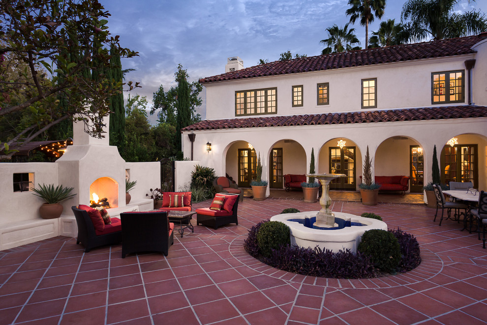 ロサンゼルスにある広い地中海スタイルのおしゃれな中庭のテラス (タイル敷き、日よけなし、屋外暖炉) の写真