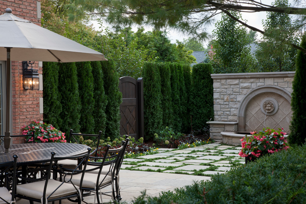 Large traditional back patio in Detroit with natural stone paving.