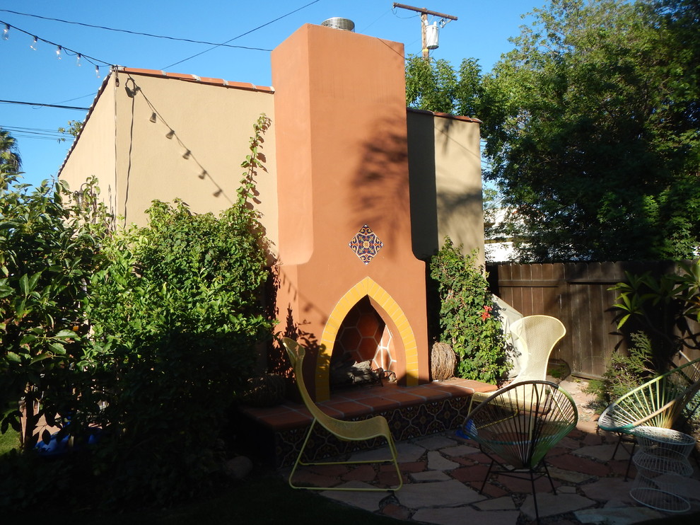 This is an example of a medium sized mediterranean back patio in Los Angeles with a fire feature, no cover and natural stone paving.