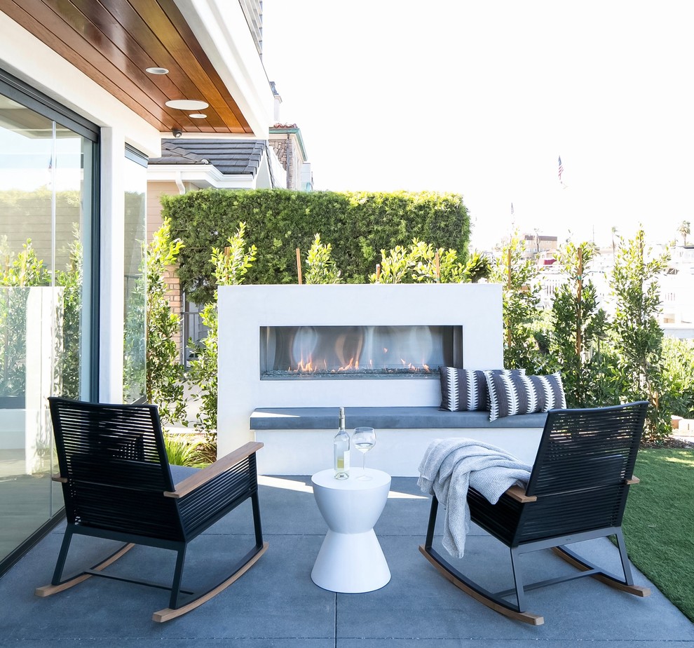 ロサンゼルスにある高級な広いコンテンポラリースタイルのおしゃれな裏庭のテラス (コンクリート板舗装	、日よけなし、屋外暖炉) の写真