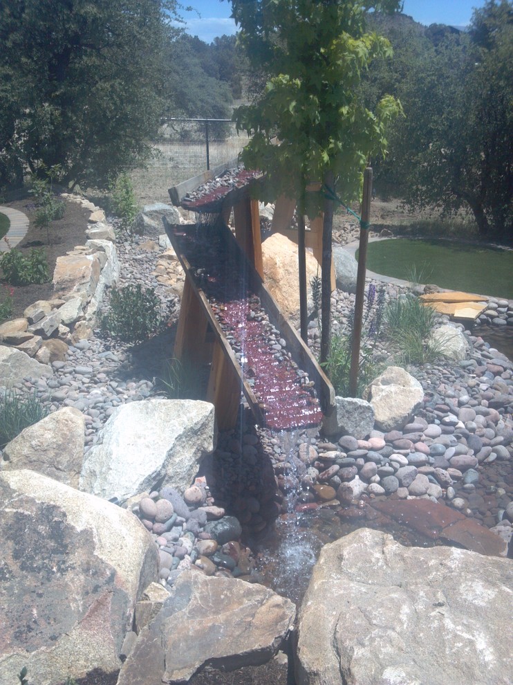 Medium sized rustic back patio in Phoenix with a water feature and concrete paving.