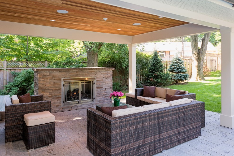 This is an example of a large traditional back patio in Toronto with a fire feature, concrete paving and a roof extension.