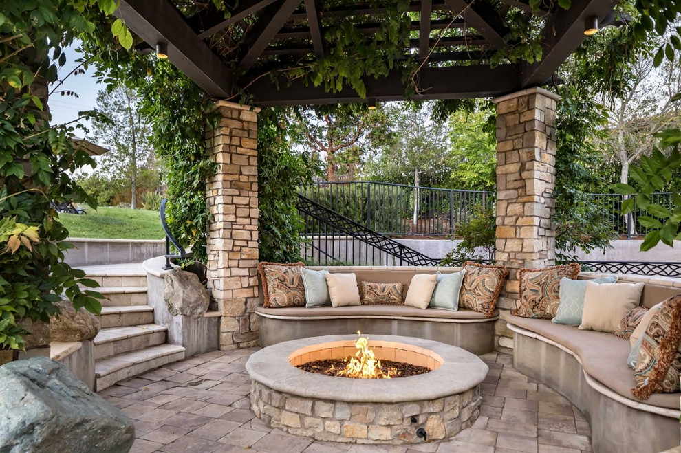 Foto de patio clásico de tamaño medio en patio trasero con cenador, brasero y adoquines de piedra natural