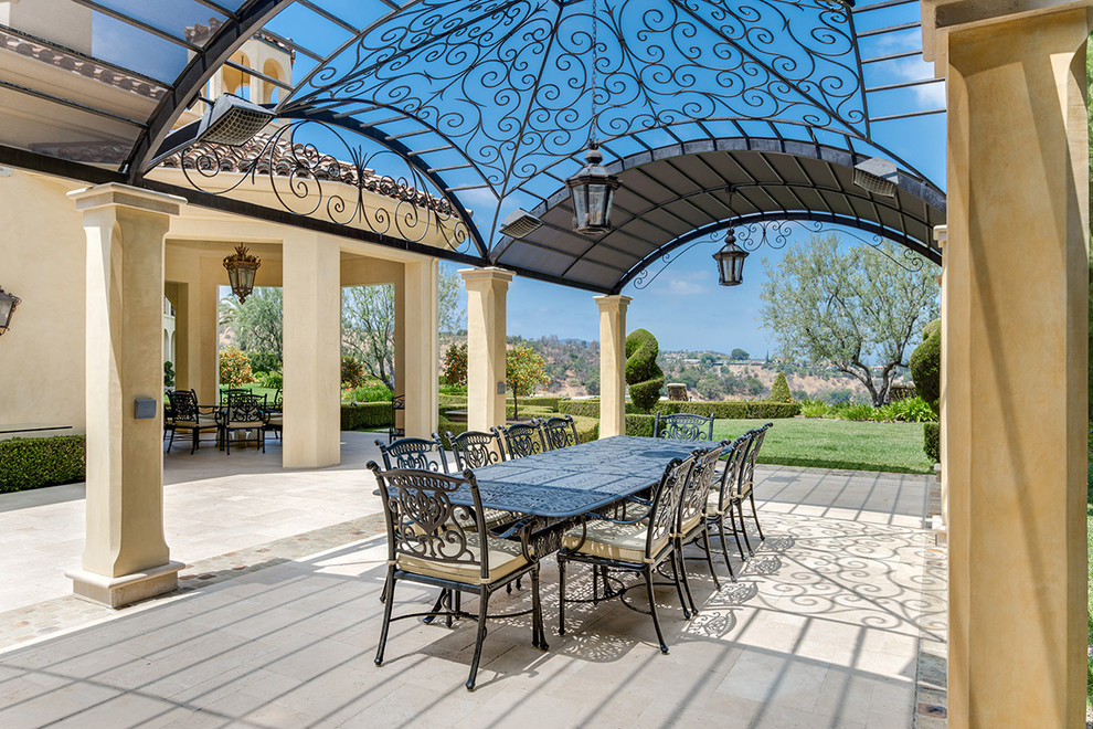 Esempio di un grande patio o portico mediterraneo dietro casa con piastrelle e una pergola
