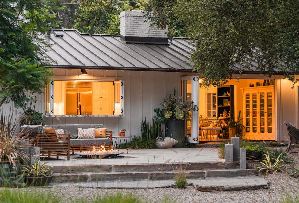 Ejemplo de patio de estilo de casa de campo grande sin cubierta en patio trasero con brasero y adoquines de hormigón