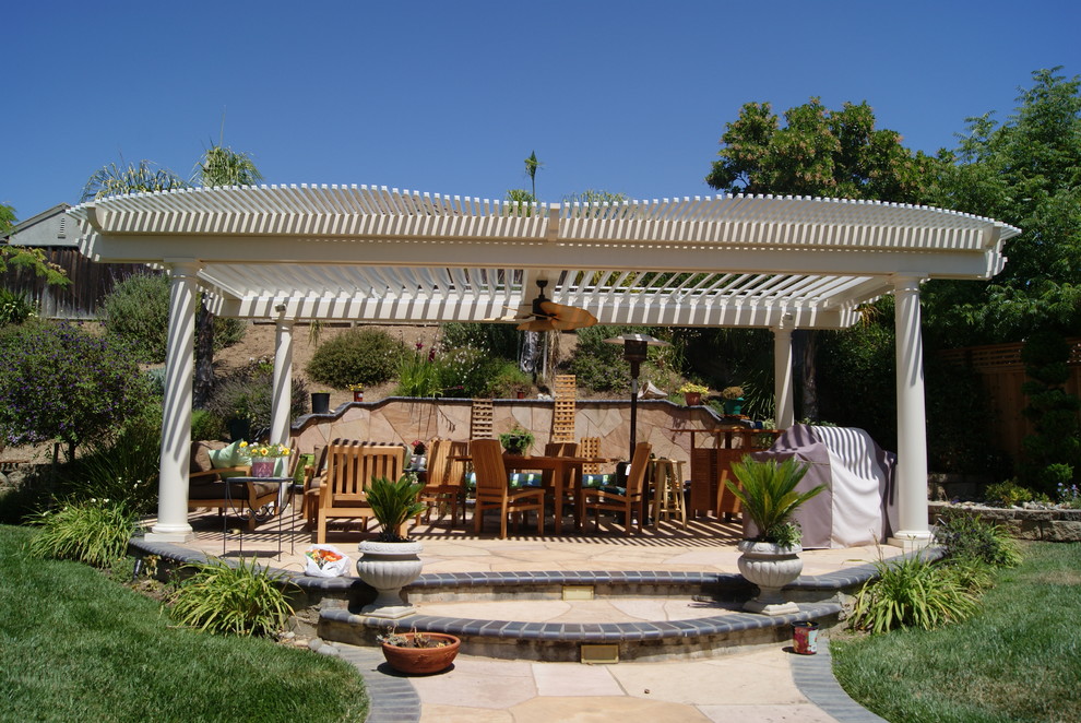 Bild på en mellanstor vintage uteplats på baksidan av huset, med en öppen spis, naturstensplattor och en pergola