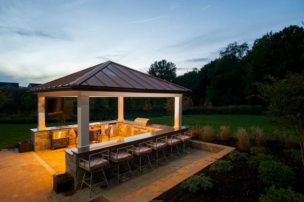 Aménagement d'une grande terrasse arrière classique avec une cuisine d'été, des pavés en brique et un gazebo ou pavillon.