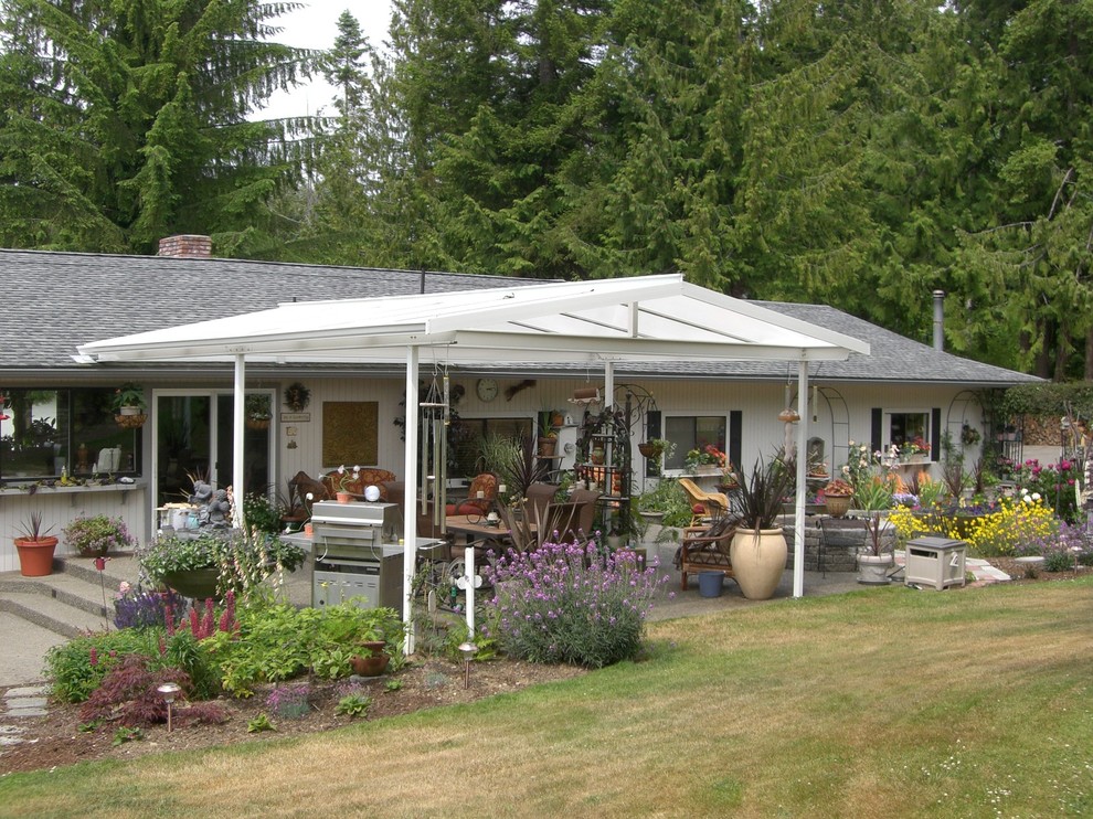 Diseño de patio campestre de tamaño medio en patio trasero con cocina exterior, losas de hormigón y toldo