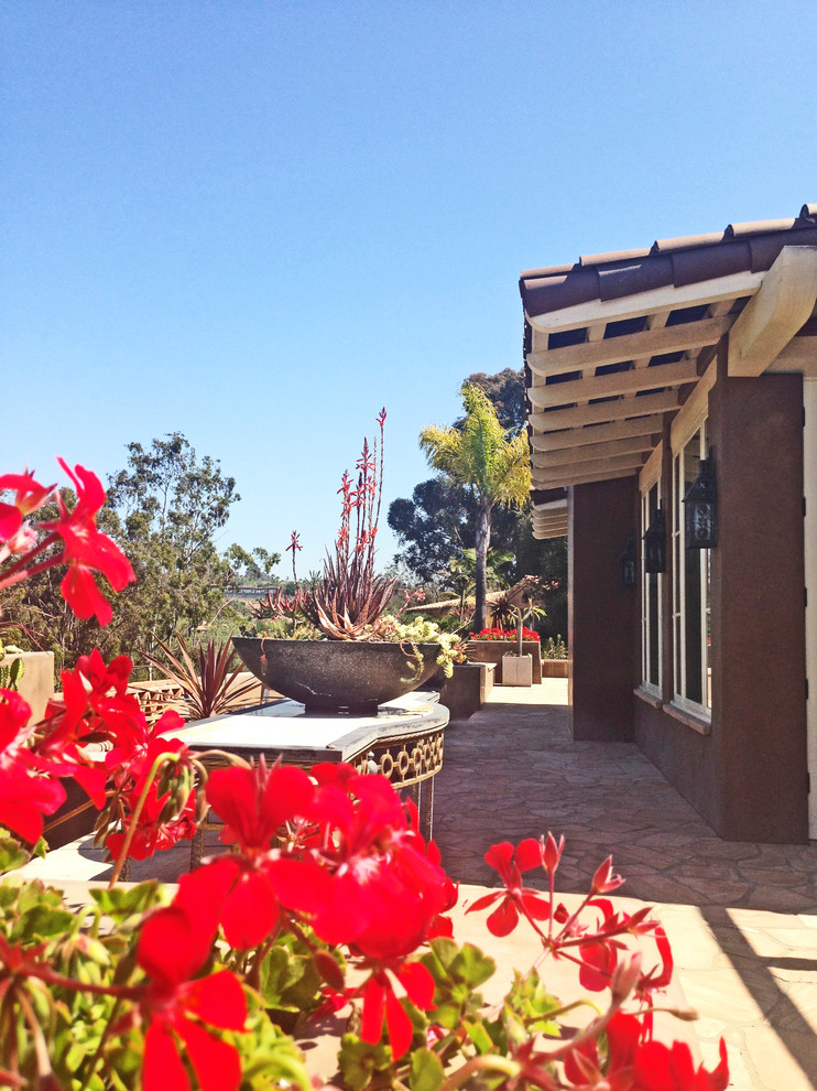 Großer Mediterraner Patio hinter dem Haus mit Kübelpflanzen und Natursteinplatten in San Diego