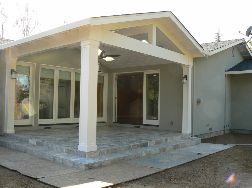 Esempio di un patio o portico eclettico di medie dimensioni e dietro casa con piastrelle e un tetto a sbalzo
