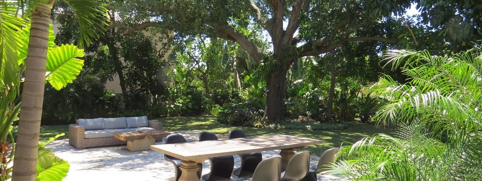 Large world-inspired back patio in Miami with natural stone paving and no cover.