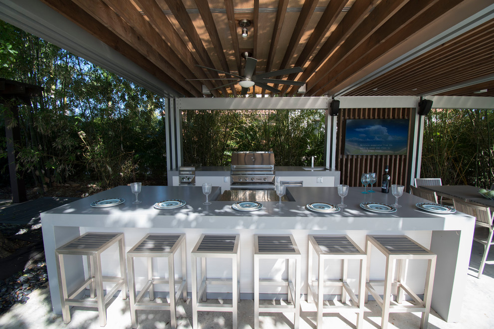 Patio kitchen - large contemporary backyard concrete paver patio kitchen idea in Miami with a pergola