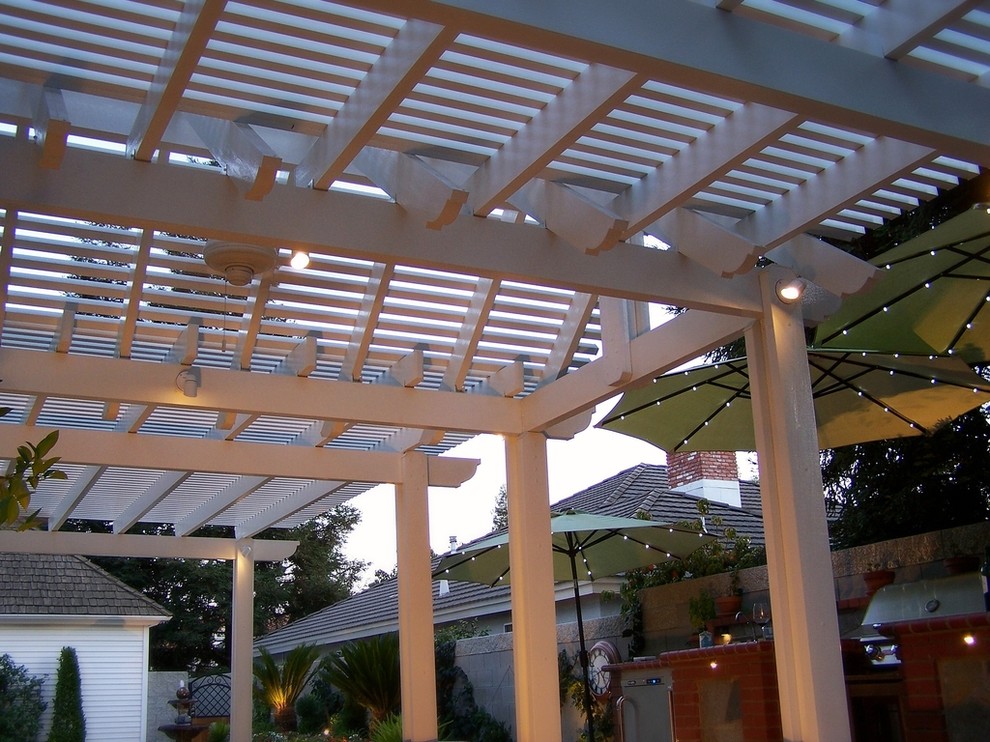Idée de décoration pour une grande terrasse arrière design avec une cuisine d'été, des pavés en pierre naturelle et une pergola.