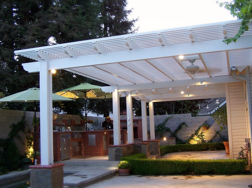 Große Klassische Pergola hinter dem Haus mit Outdoor-Küche und Natursteinplatten in Sonstige