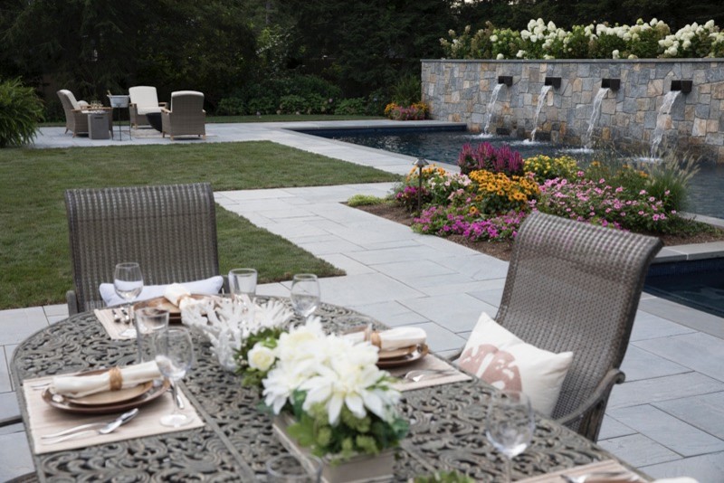 Photo of an expansive contemporary back patio in New York with an outdoor kitchen, natural stone paving and no cover.