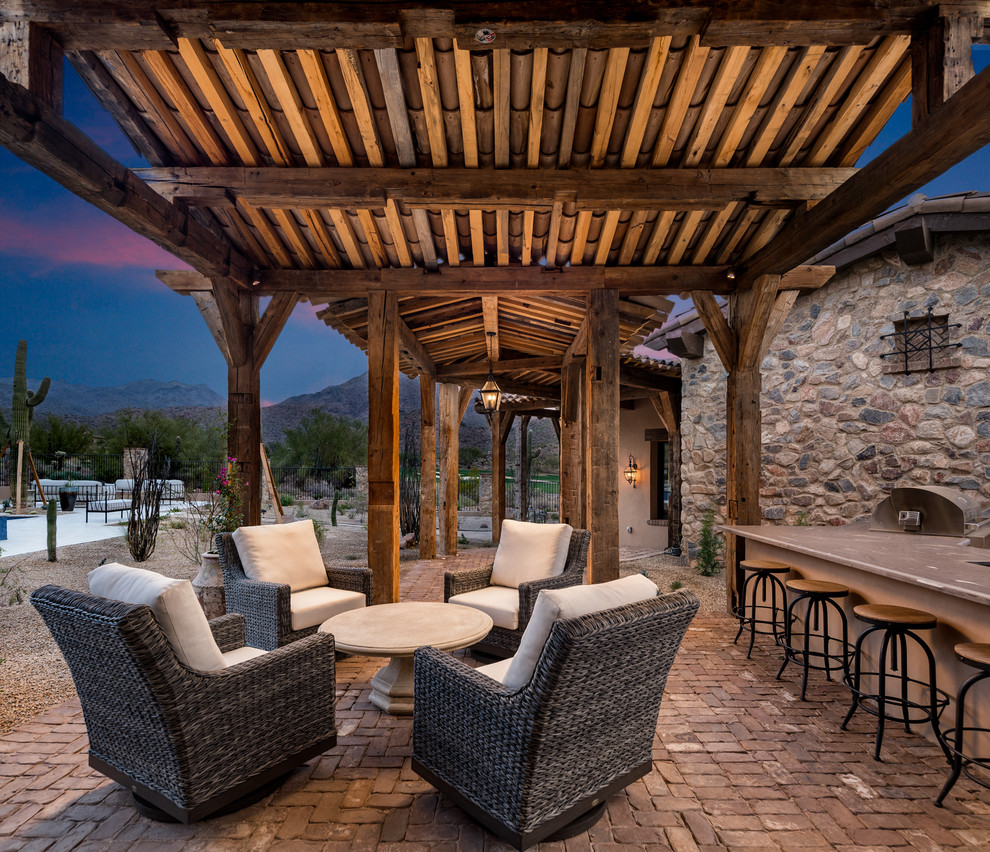 Idée de décoration pour une très grande terrasse arrière avec une cuisine d'été, des pavés en pierre naturelle et un auvent.
