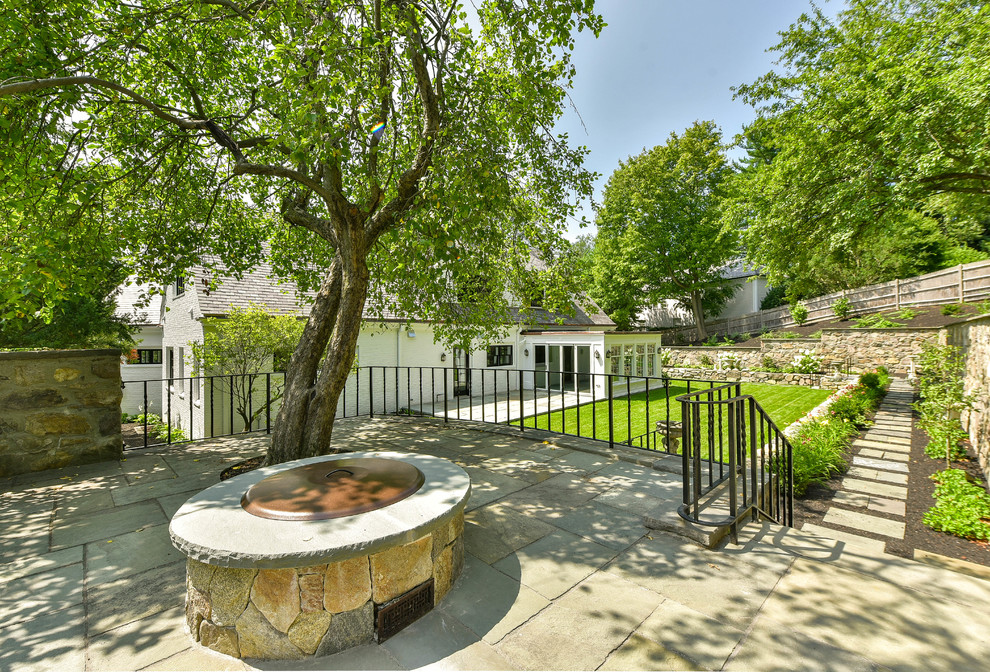 Esempio di un patio o portico chic di medie dimensioni e dietro casa con un focolare, pavimentazioni in pietra naturale e nessuna copertura