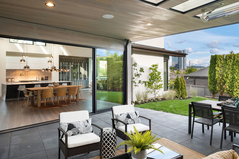 Design ideas for a large contemporary back patio in Seattle with a fireplace, concrete paving and a roof extension.