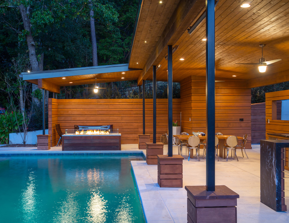Réalisation d'une grande terrasse arrière minimaliste avec un foyer extérieur, du béton estampé et un gazebo ou pavillon.