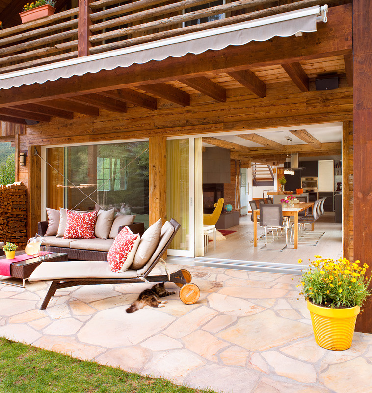 Patio - mid-sized rustic side yard stone patio idea in Denver with a roof extension