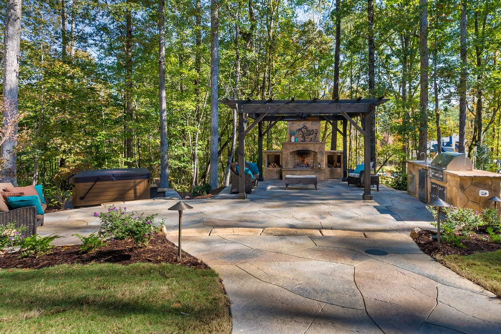 Cette image montre une grande terrasse arrière minimaliste avec une cuisine d'été, du béton estampé et une pergola.