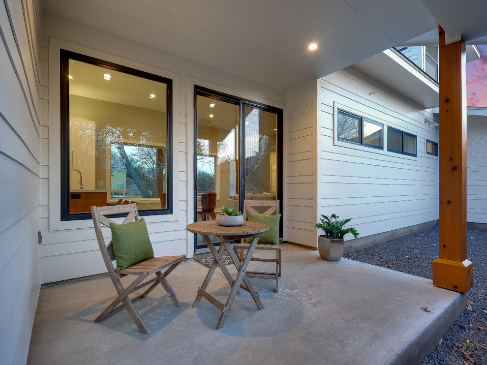 Esempio di un piccolo patio o portico minimal dietro casa con lastre di cemento e un tetto a sbalzo