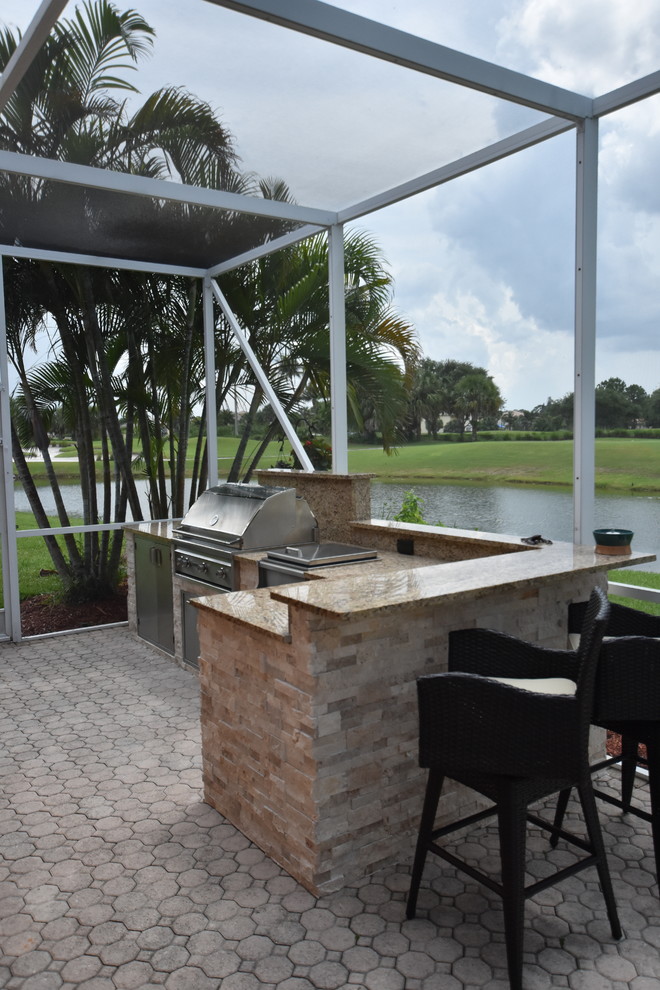 World-inspired back patio in Miami with an outdoor kitchen, brick paving and no cover.