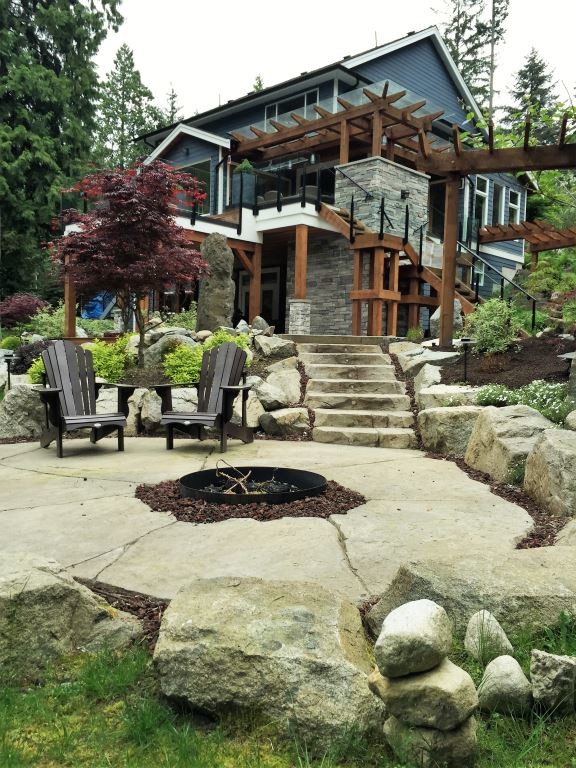 Patio - large rustic backyard stone patio idea in Vancouver with a fire pit and a pergola