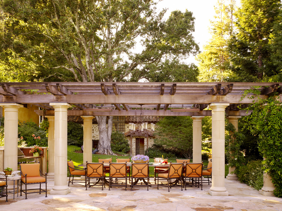 Cette image montre une terrasse méditerranéenne avec une cuisine d'été, des pavés en pierre naturelle et une pergola.