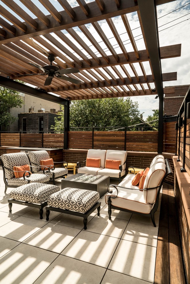Idée de décoration pour une terrasse arrière design de taille moyenne avec un foyer extérieur, du carrelage et une pergola.