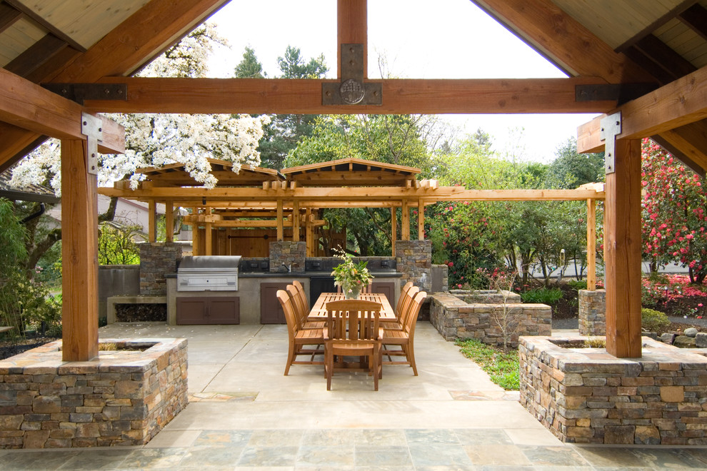 Inspiration for a large rustic courtyard patio in Portland with an outdoor kitchen, natural stone paving and a roof extension.