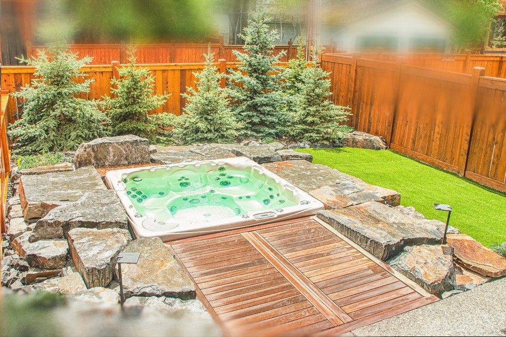 Mid-sized mountain style backyard stone patio fountain photo in Calgary with no cover