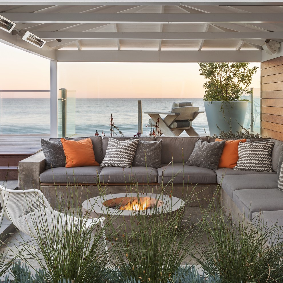 Exemple d'une terrasse latérale bord de mer avec un foyer extérieur et une pergola.