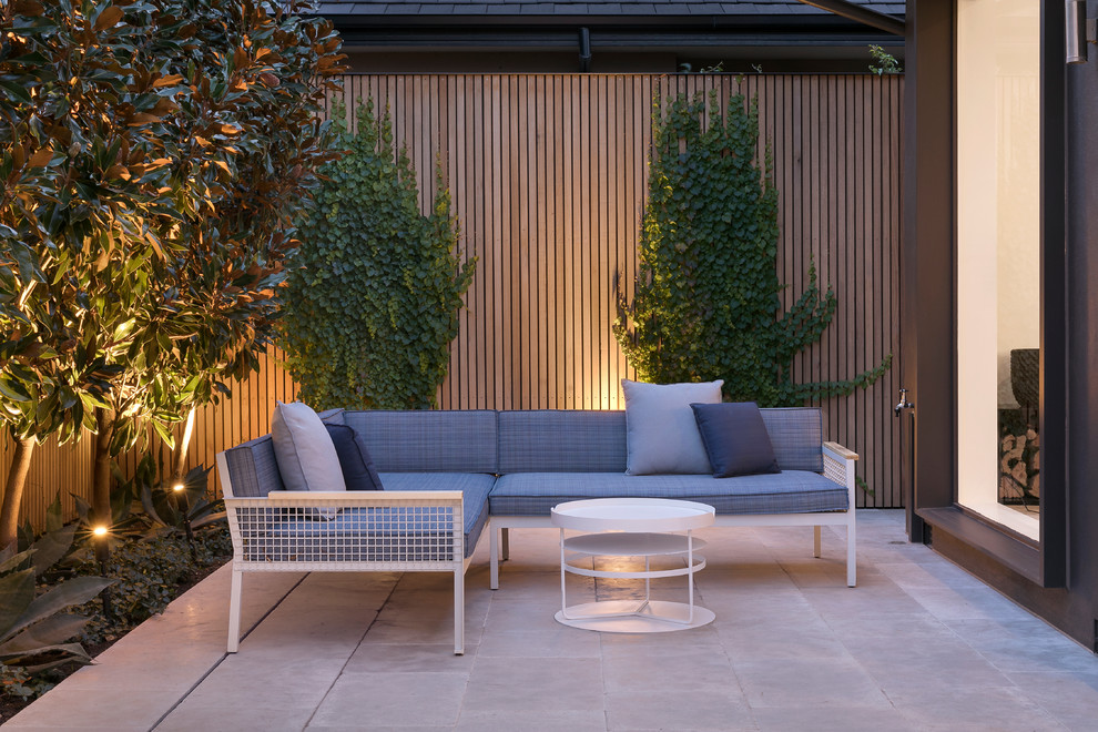This is an example of a small contemporary back patio in Melbourne with natural stone paving.