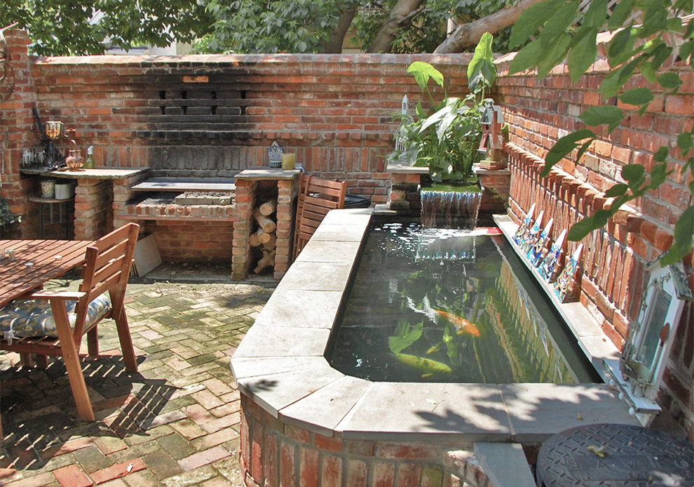 На фото: двор в стиле фьюжн с мощением клинкерной брусчаткой и летней кухней
