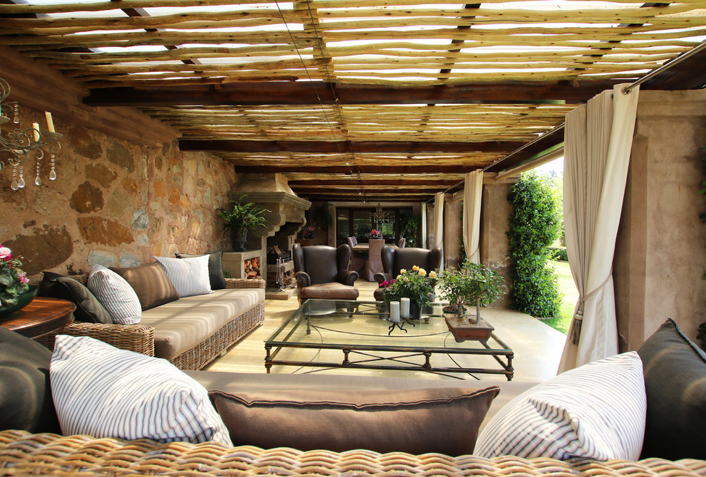 Imagen de patio mediterráneo en patio trasero con pérgola y chimenea