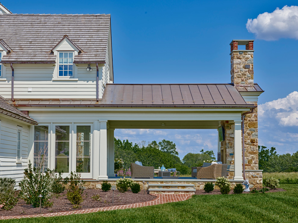Foto di un patio o portico classico dietro casa con un caminetto, pavimentazioni in pietra naturale e un tetto a sbalzo