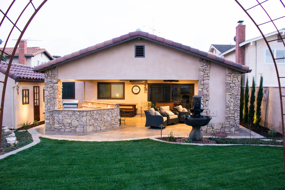 Immagine di un patio o portico american style di medie dimensioni e dietro casa con un focolare, piastrelle e un tetto a sbalzo