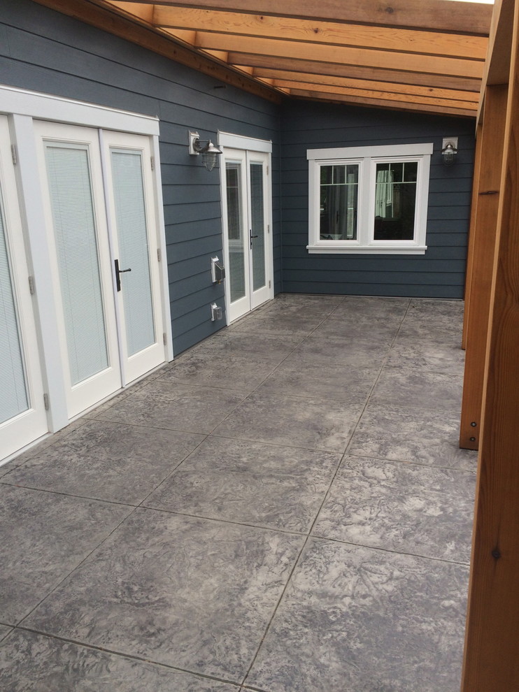 Immagine di un patio o portico american style davanti casa con cemento stampato e una pergola