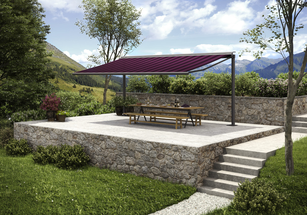 Aménagement d'une terrasse arrière de taille moyenne avec un auvent, une cuisine d'été et des pavés en pierre naturelle.