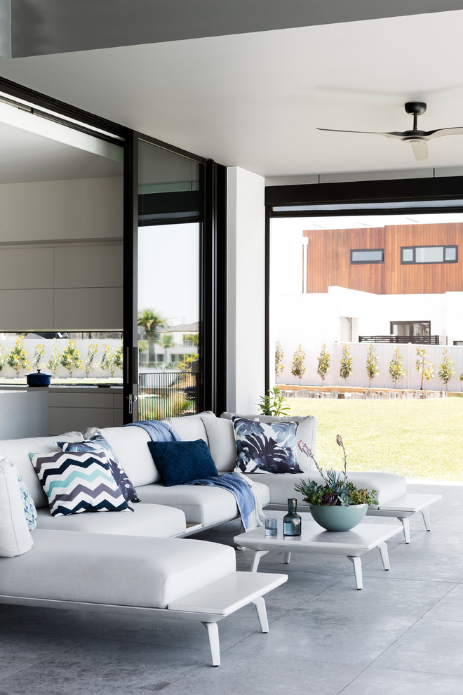 Immagine di un patio o portico minimal dietro casa con piastrelle e una pergola