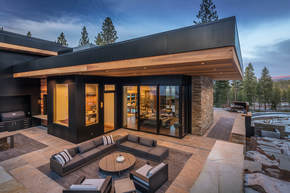 Cette image montre une grande terrasse arrière minimaliste avec une cuisine d'été, des pavés en pierre naturelle et aucune couverture.