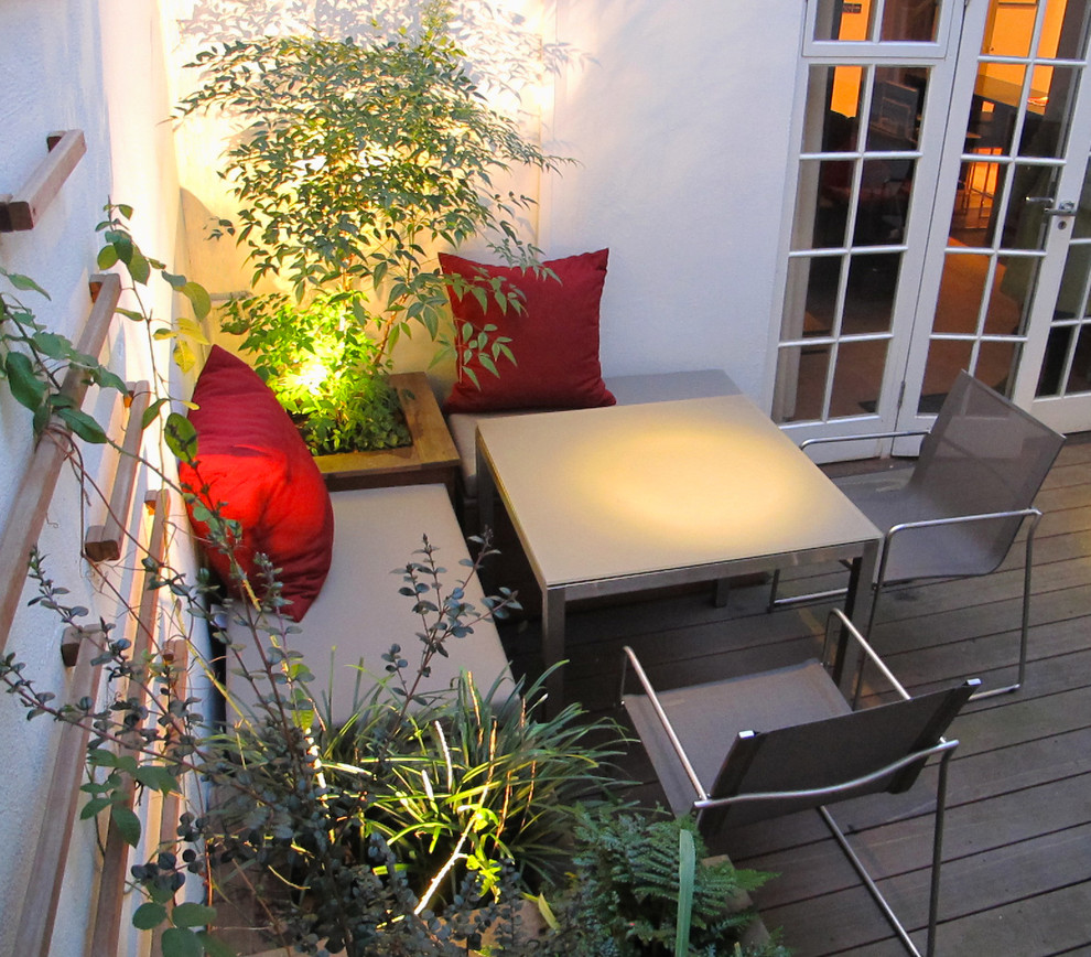 На фото: маленький двор на внутреннем дворе в современном стиле с растениями в контейнерах и настилом для на участке и в саду
