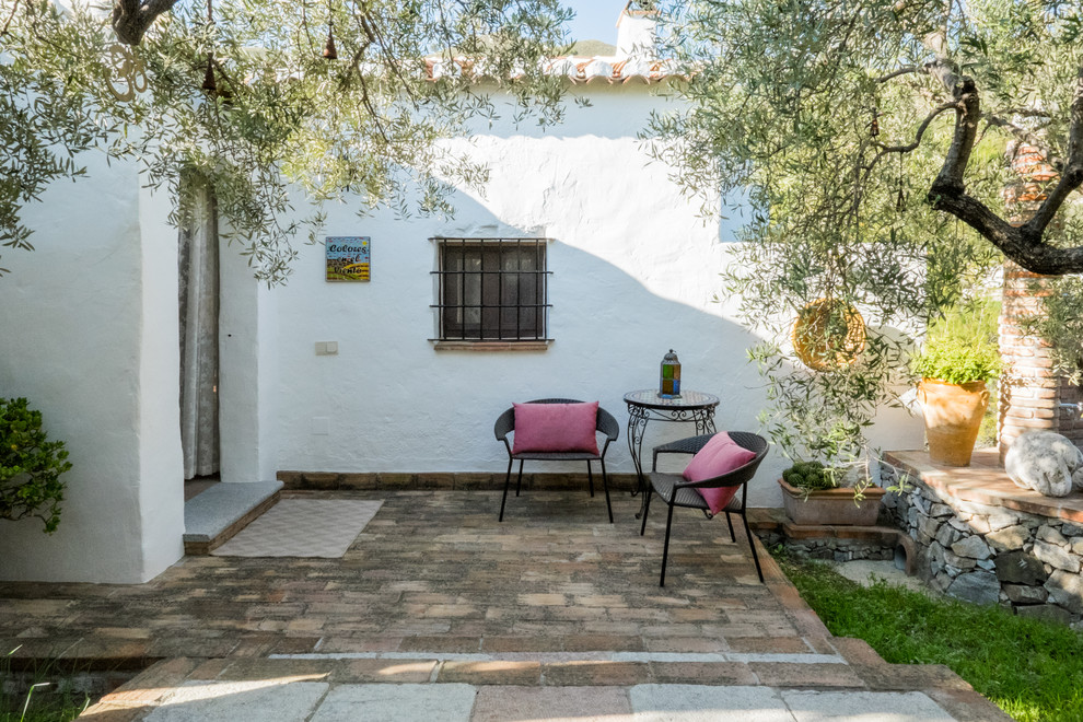 Immagine di un patio o portico mediterraneo dietro casa e di medie dimensioni con pavimentazioni in mattoni e nessuna copertura