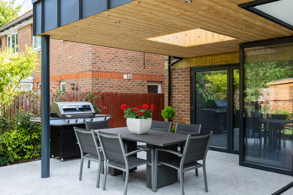 Design ideas for a contemporary back patio in Hertfordshire with an outdoor kitchen, concrete slabs and a roof extension.