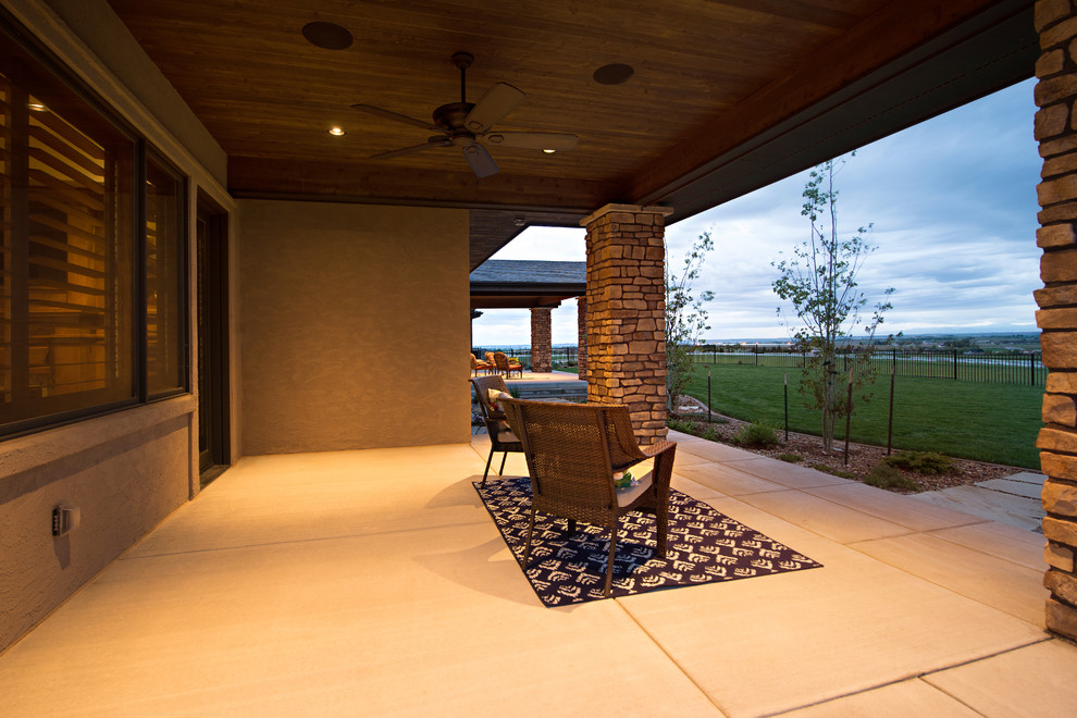 Cette image montre une très grande terrasse arrière craftsman avec une dalle de béton et une extension de toiture.