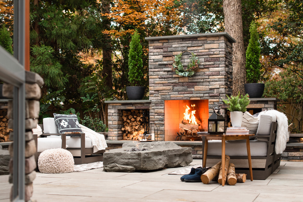 Example of a mid-sized minimalist backyard stone patio design in Richmond with a fireplace